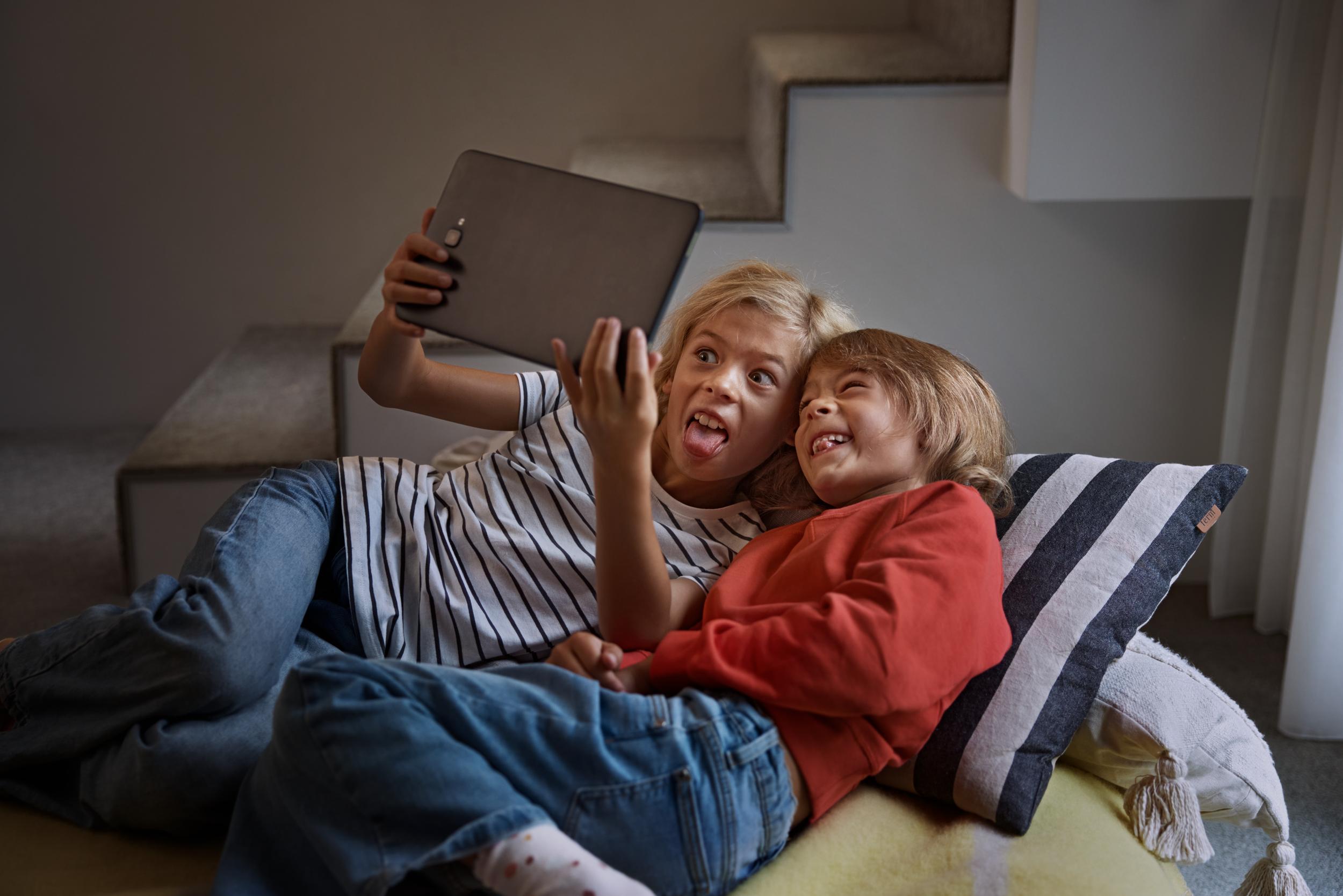 Två barn leker med en surfplatta.