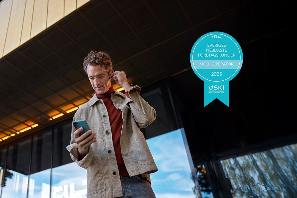Man med mobiltelefon utanför kontor, pris för bästa operatör mobil företag