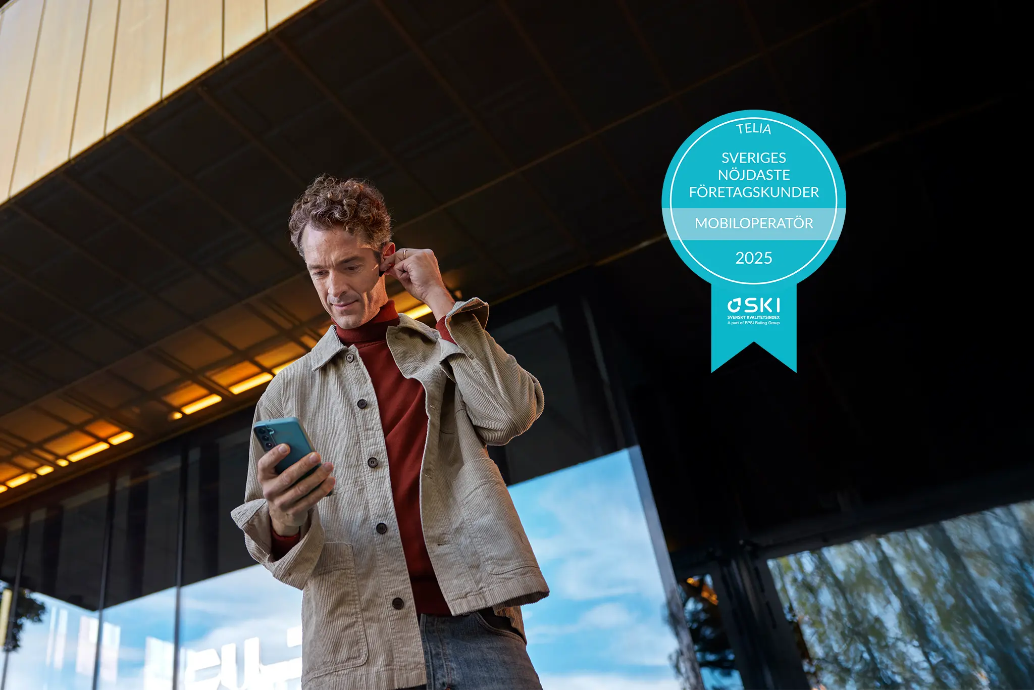 Man med mobiltelefon utanför kontor, pris för bästa operatör mobil företag
