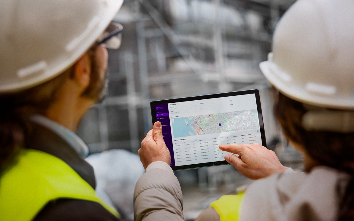 Man och kvinna med arbetshjälmar tittar på surfplatta eller platta eller padda