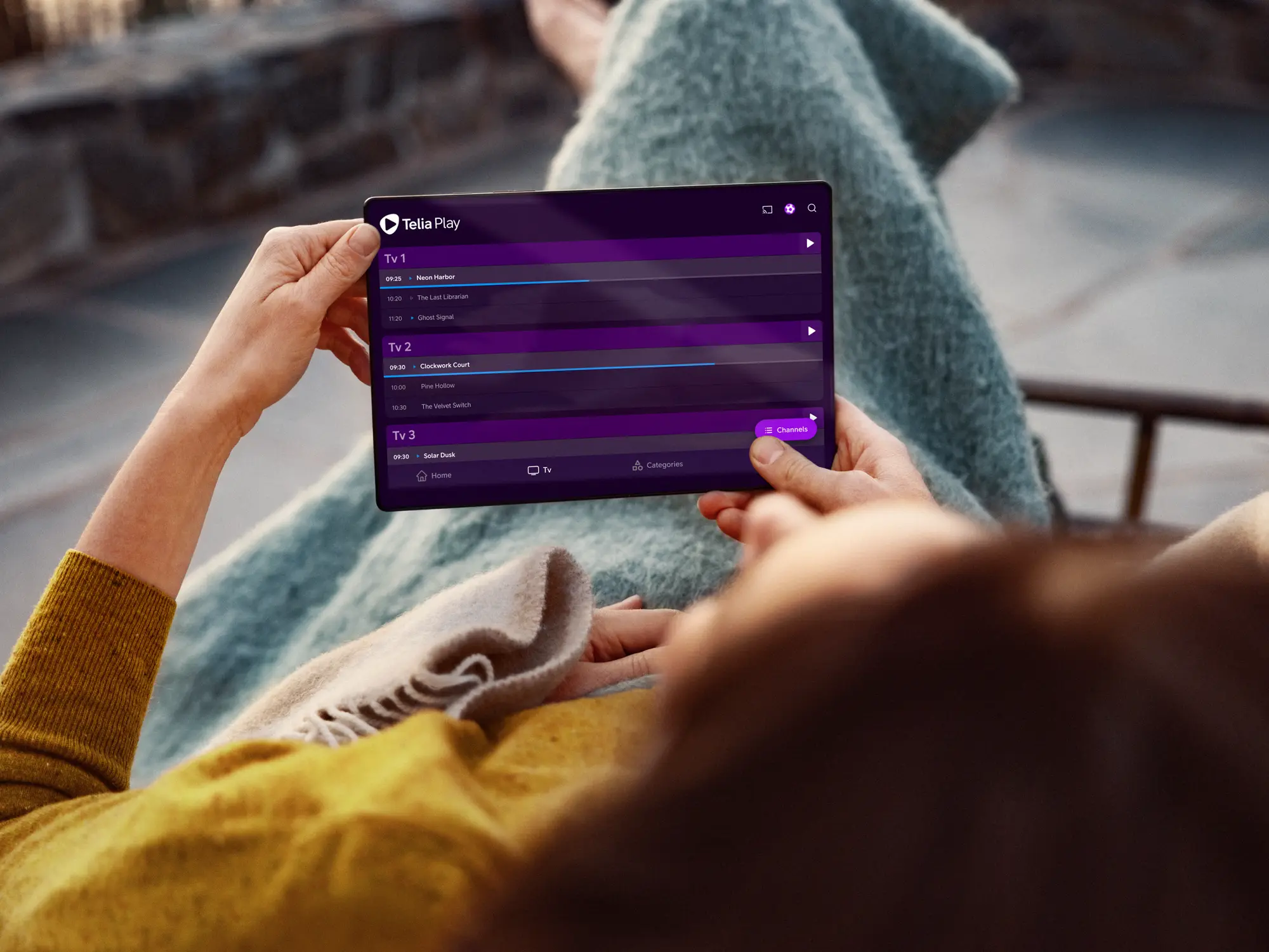 Person lutar sig tillbaka och tittar på Telia Play på sin surfplatta. Titta på hela ditt tv-utbud samlat på ett och samma ställe, direkt i Telia Play-appen.