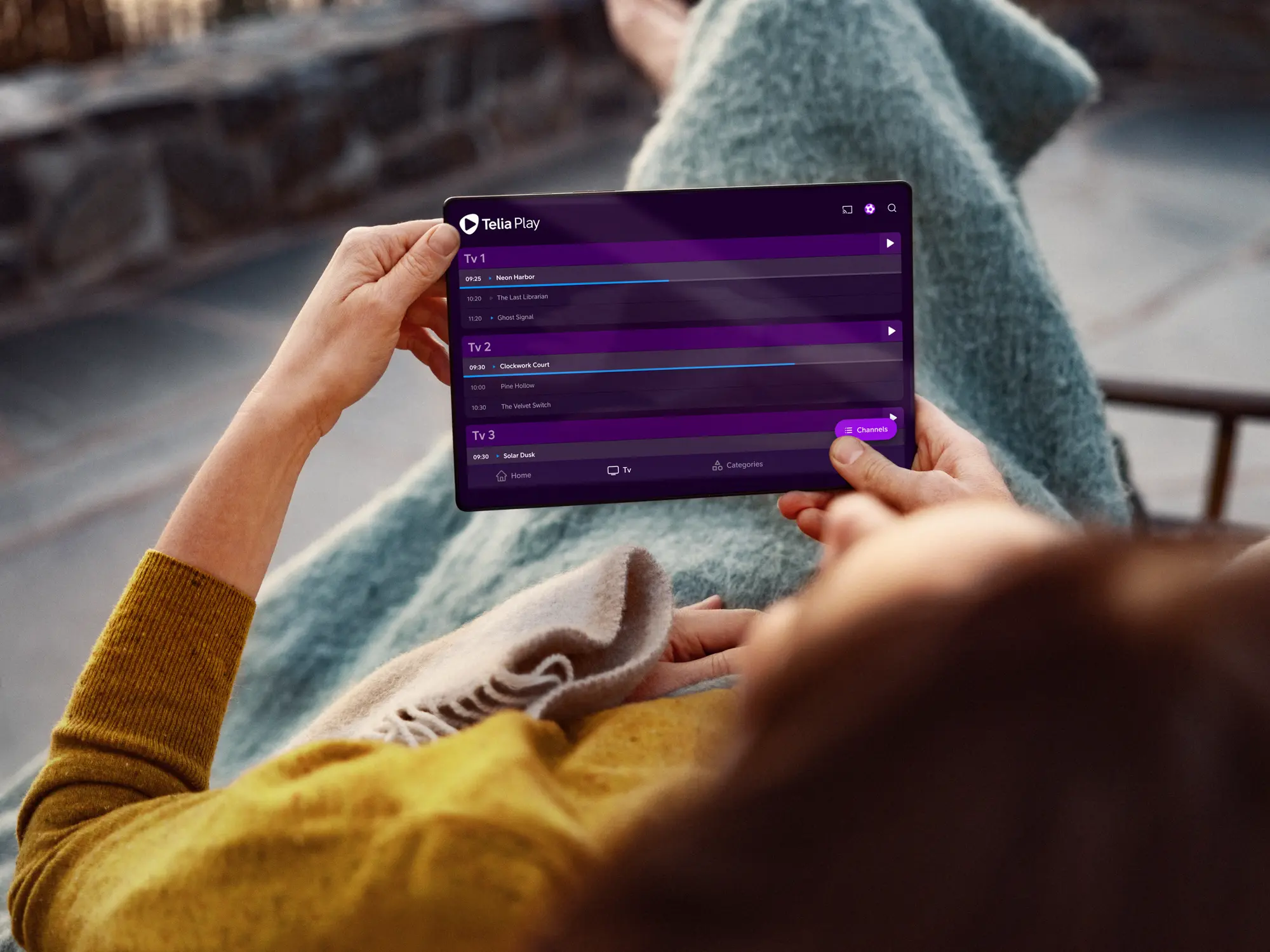 Person lutar sig tillbaka och tittar på Telia Play på sin surfplatta. Titta på hela ditt tv-utbud samlat på ett och samma ställe, direkt i Telia Play-appen.