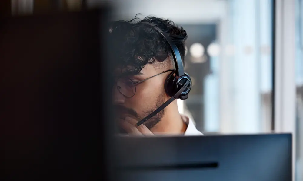 En man med hörlurar som tittar på en dator.