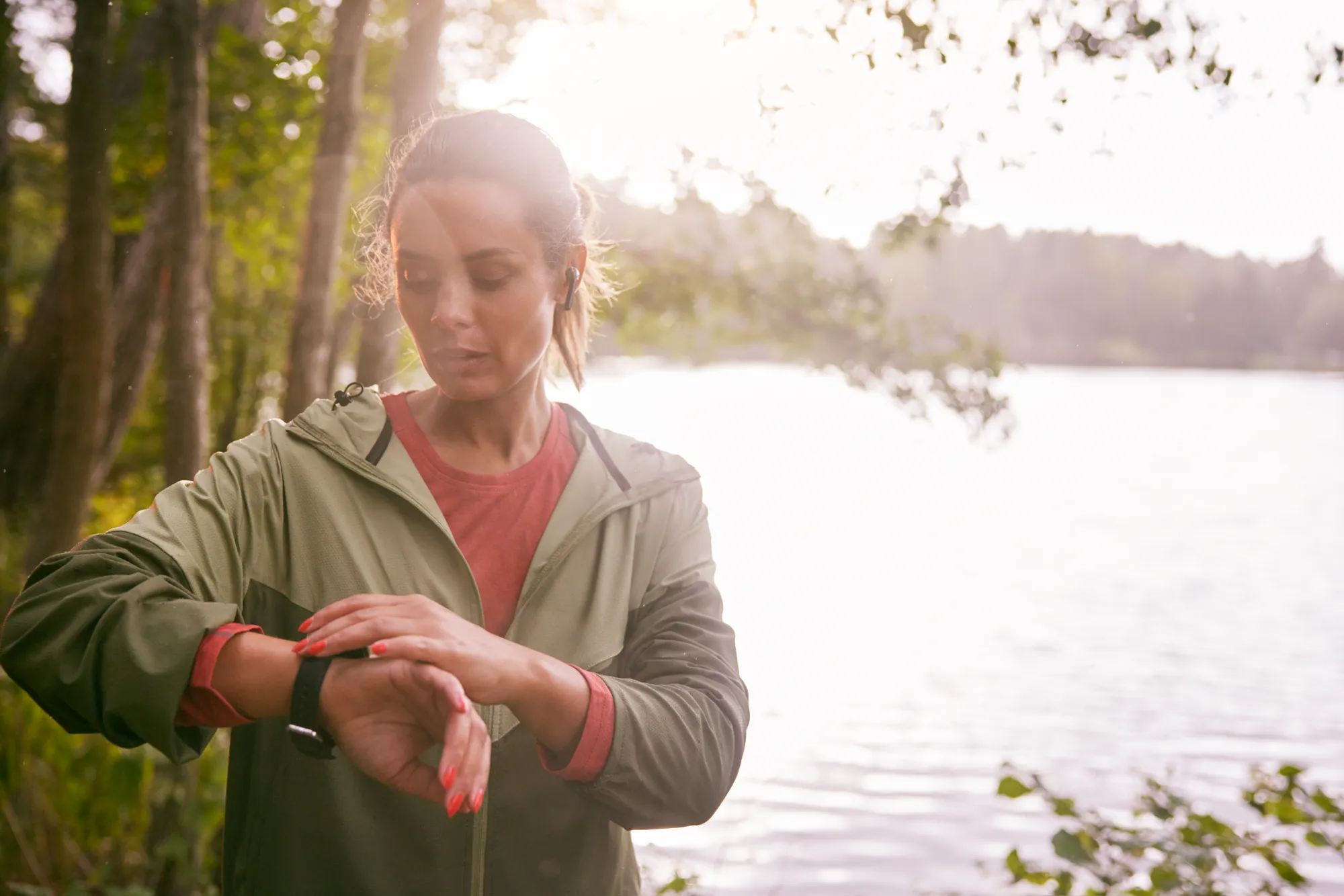 Kvinna kollar sin smartklocka vid en sjö.