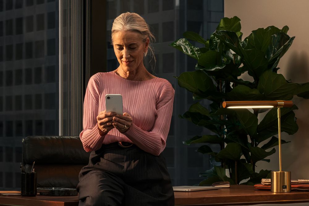 Kvinna med iphone 17e på modernt kontor.