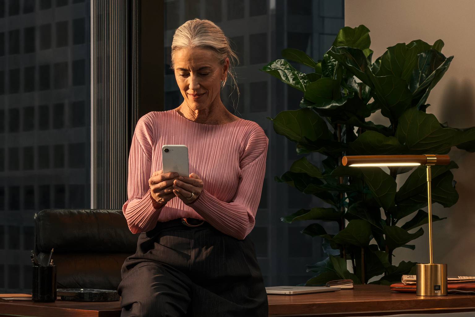 Kvinna med iphone 17e på modernt kontor.