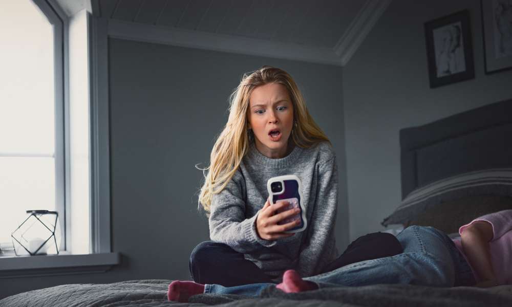 Kvinna tittar på sin mobil med oroligt ansiktsuttryck.