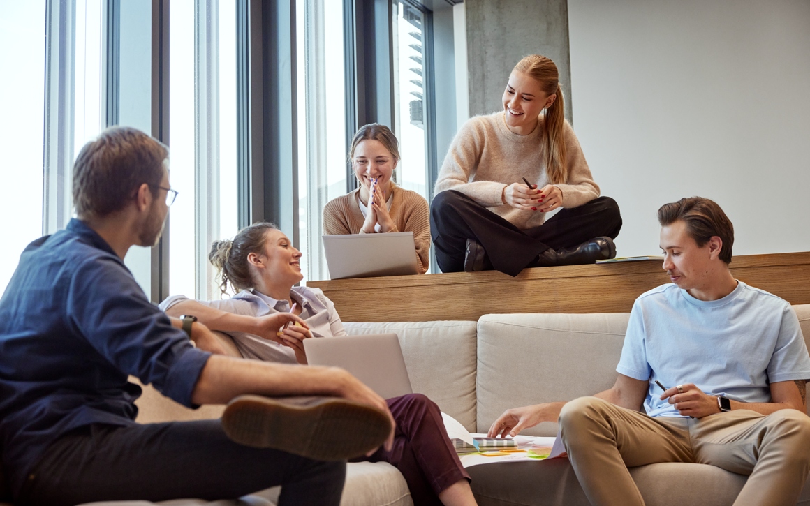Kollegor har workshop på ljust kontor med laptops och post-its.