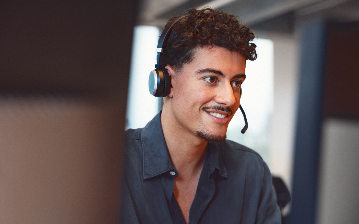 Ung man med headet arbetar med IT-support på kontor.