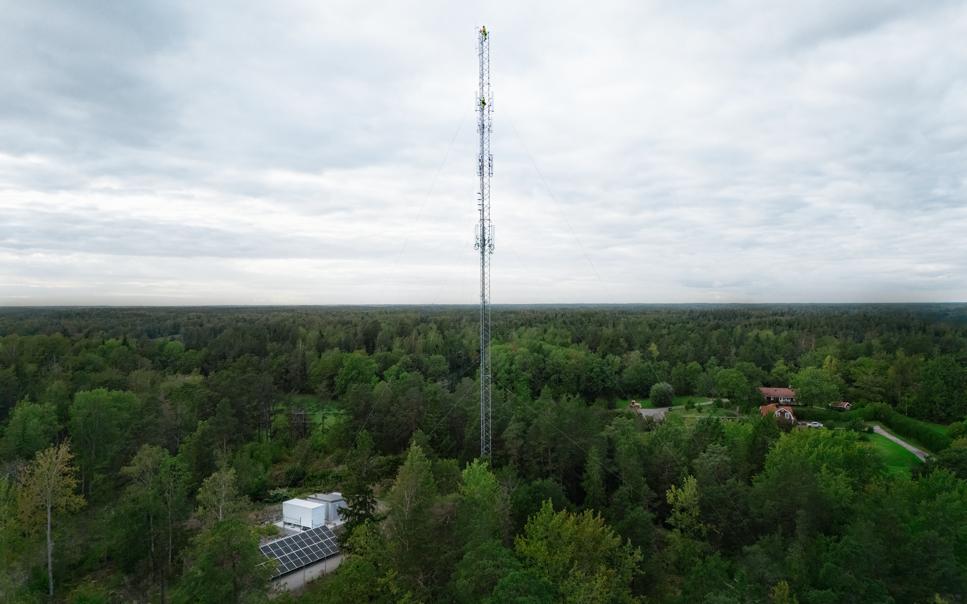 Telemast i grönskande glesbygd sedd på avstånd.