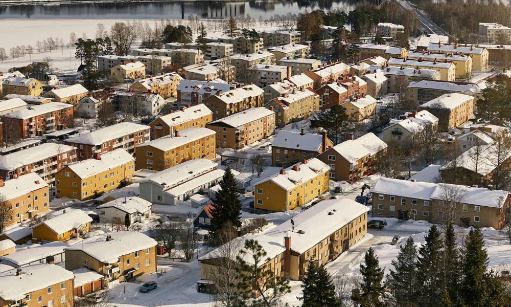 Ett lägenhetskomplex i ett vinterlandskap, där marken och hustaken är täckta av snö som illustrerar ett exempel på var det passar alldeles utmärkt med bredband via fiber.