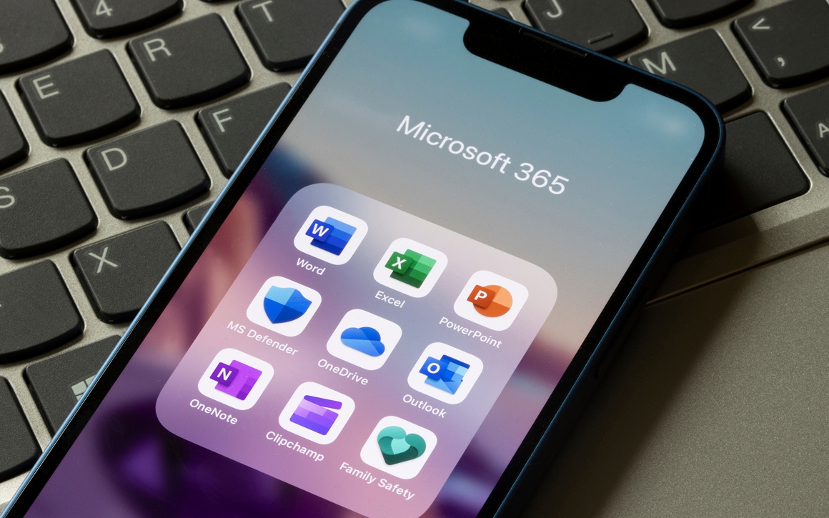 Mobiltelefon med Microsoft 365-appar ligger på laptop.