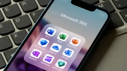 Mobiltelefon med Microsoft 365-appar ligger på laptop.