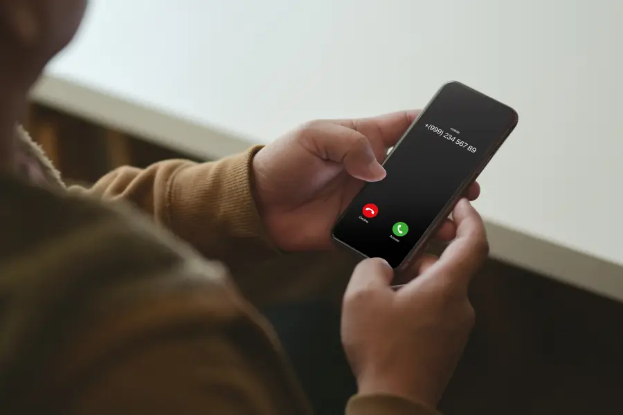 En person håller en mobiltelefon med ett misstänkt nummer på skärmen.