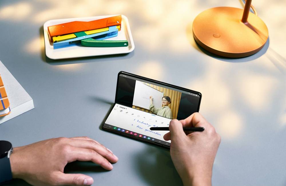 Samsung Galaxy Z Fold5 med penna i hand på skrivbord.