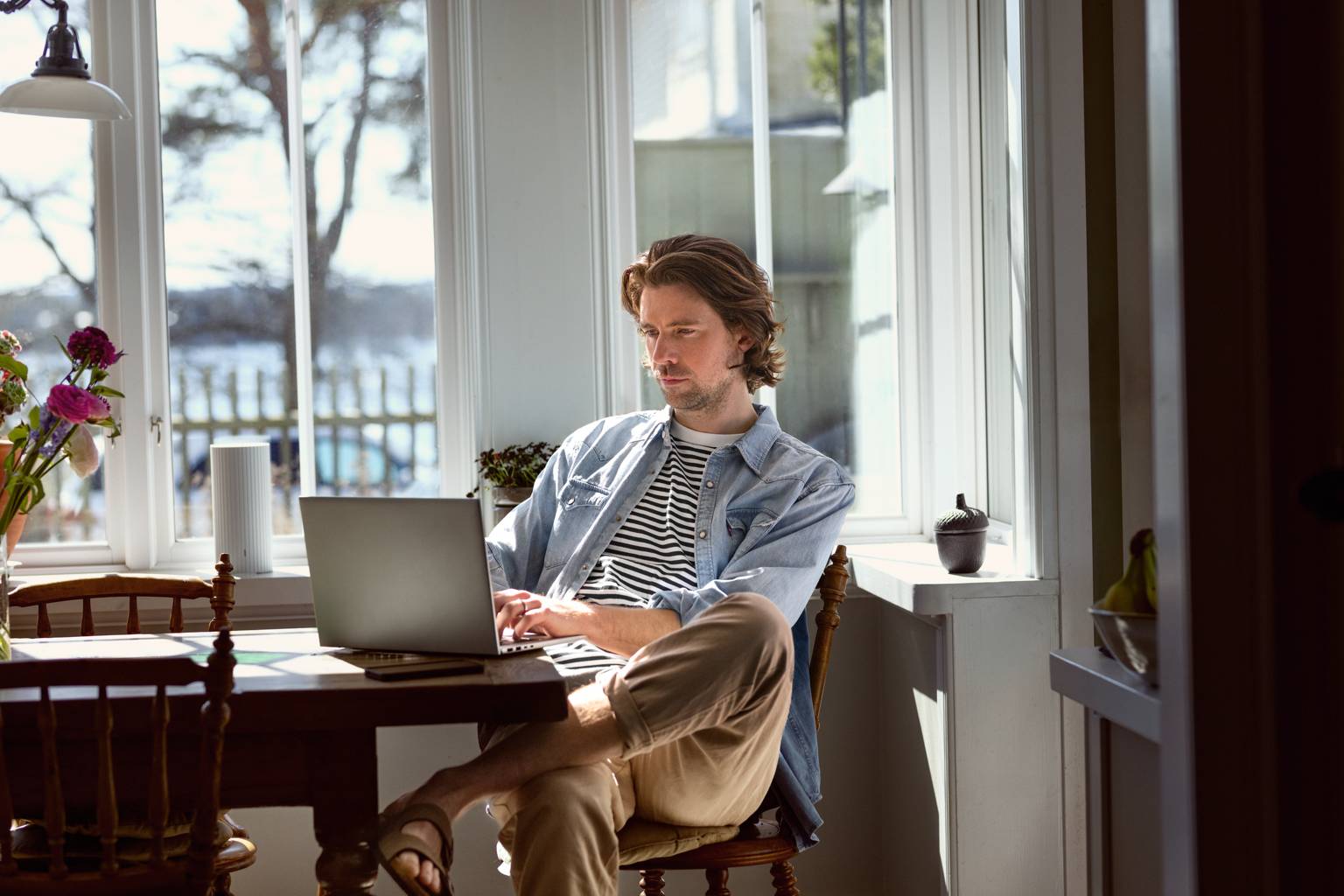 Man med laptop i knät jobbar hemma