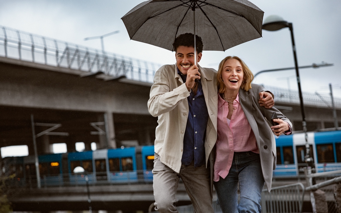 Man och kvinna som springer under ett paraply